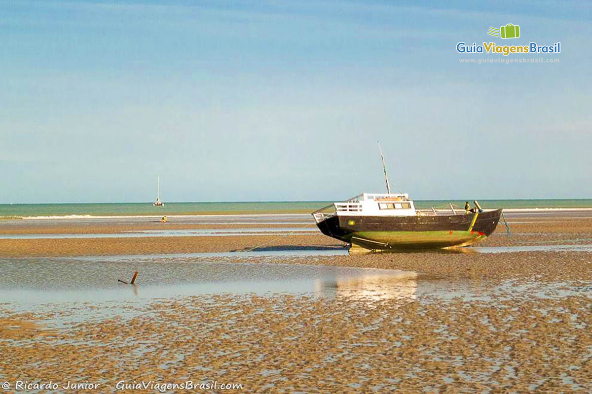 Imagem de um barco de pescador inclinado nas areias da praia Jericoacoara.